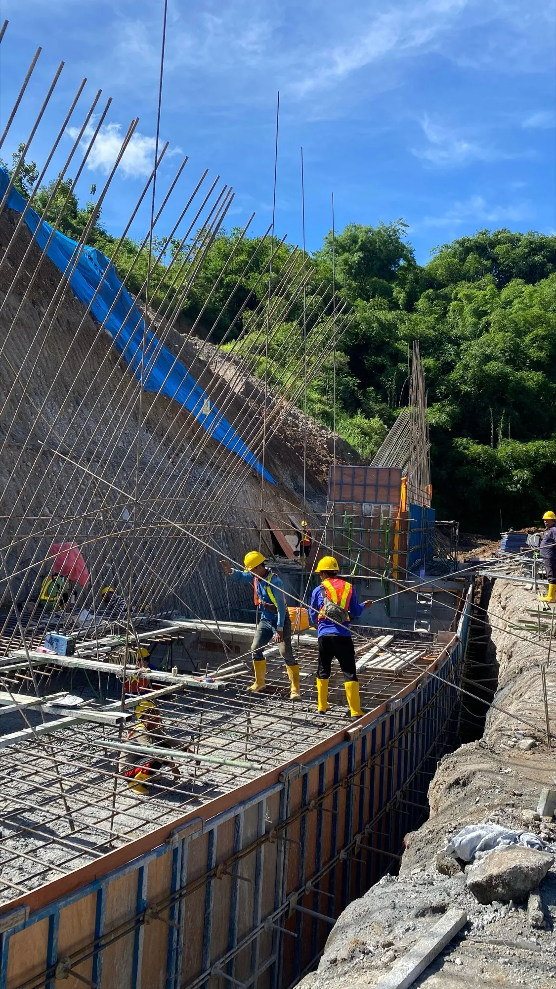 Pekerja berhelm memeriksa pembesian fondasi di lokasi proyek