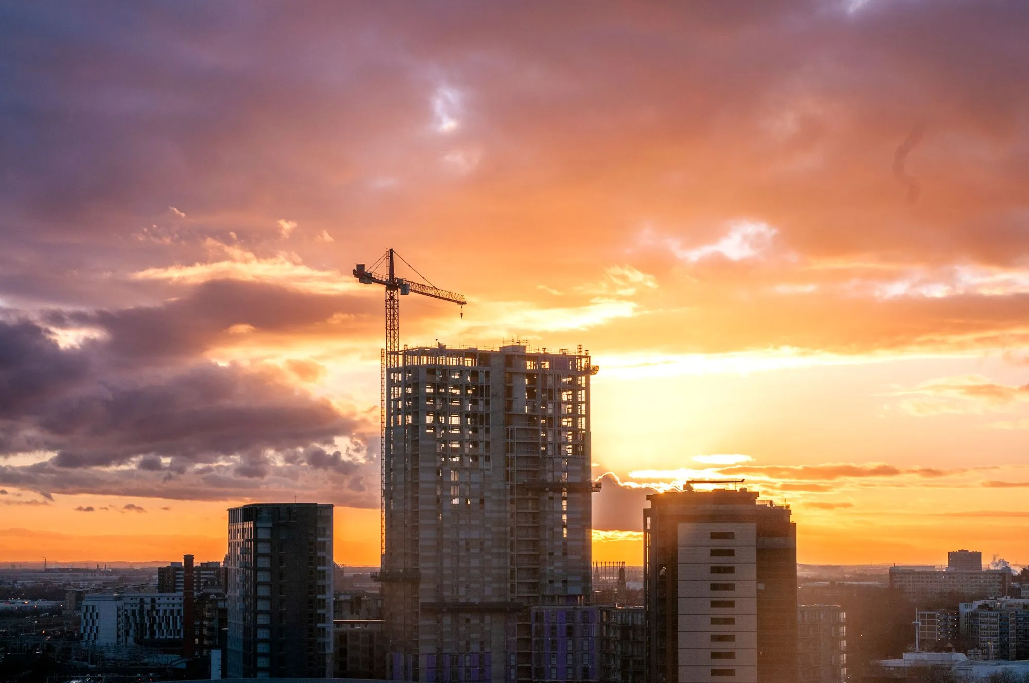 Gedung dalam tahap konstruksi dengan crane saat matahari terbenam